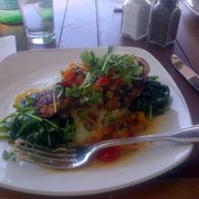 Pan sauteed sea bass with mashed and spinach, covered in cherry tomatoes.